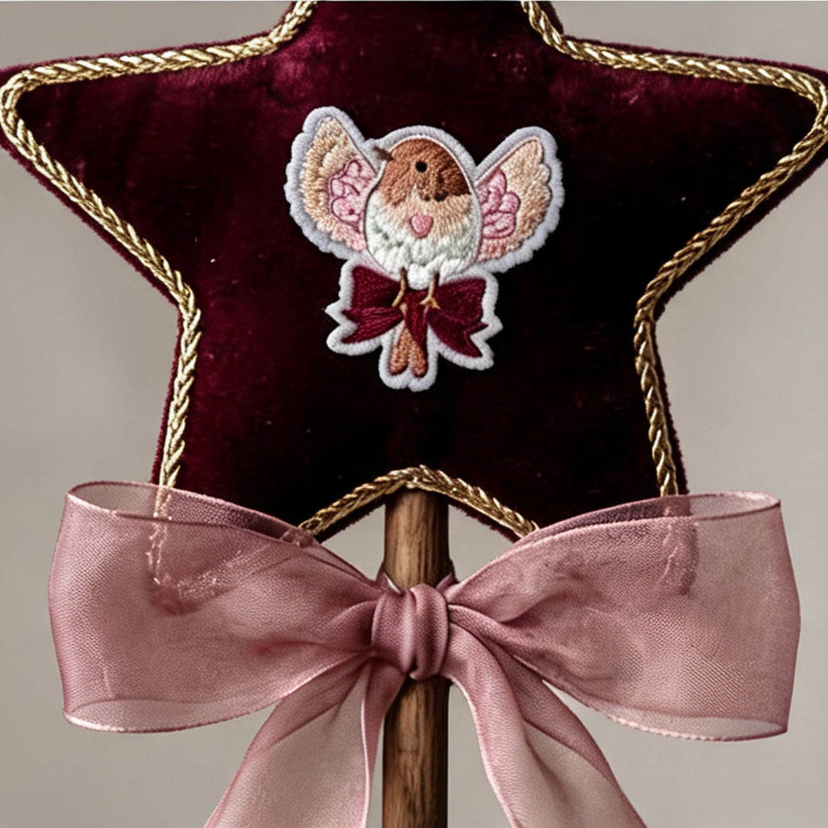 Close up of the embroidered robin applique and gold cord trim on the burgundy velvet star